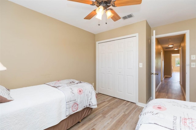 bedroom featuring light wood finished floors, a closet, visible vents, ceiling fan, and baseboards