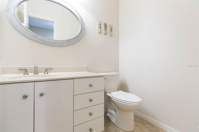 half bathroom with toilet, baseboards, vanity, and tile patterned floors