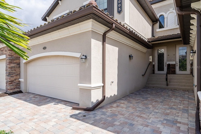 view of side of property featuring an attached garage and stucco siding