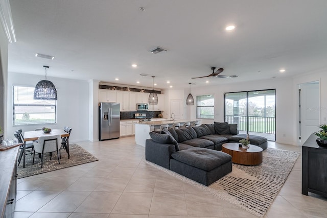 living area featuring light tile patterned floors, a ceiling fan, visible vents, and recessed lighting