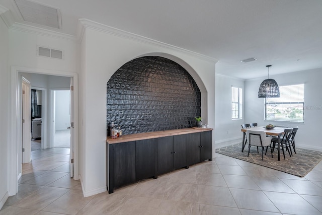 dining room featuring light tile patterned flooring, visible vents, and crown molding