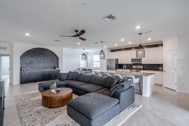 living room with ornamental molding, visible vents, ceiling fan, and light tile patterned flooring