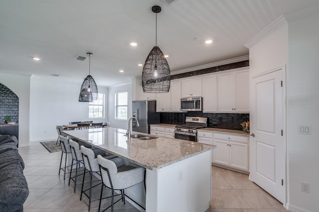 kitchen featuring pendant lighting, a center island with sink, appliances with stainless steel finishes, open floor plan, and a sink