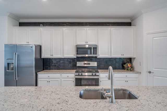 kitchen featuring a sink, white cabinets, ornamental molding, appliances with stainless steel finishes, and decorative backsplash