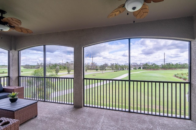 unfurnished sunroom featuring a ceiling fan and view of golf course