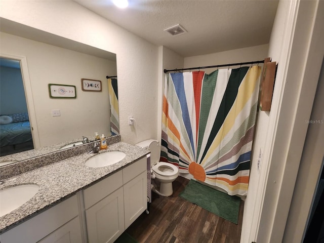 ensuite bathroom with wood finished floors, visible vents, a sink, and double vanity