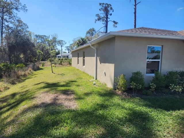 view of side of home with a shingled roof, a lawn, and stucco siding