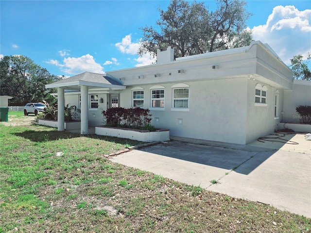 view of front facade with driveway, a front lawn, a chimney, and stucco siding