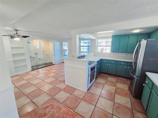 kitchen featuring a peninsula, a healthy amount of sunlight, light tile patterned floors, and stainless steel appliances