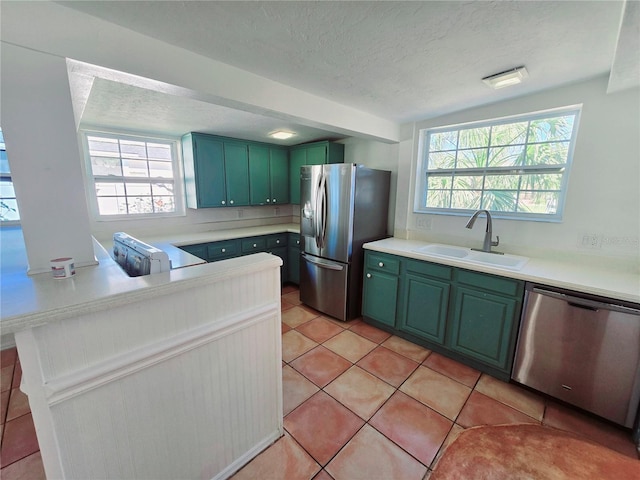 kitchen featuring a healthy amount of sunlight, appliances with stainless steel finishes, green cabinetry, and a sink