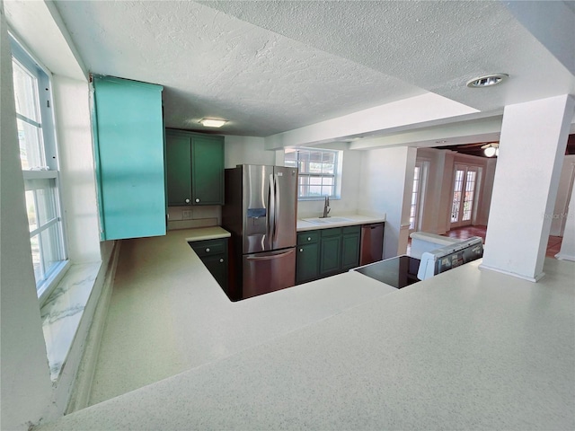 kitchen featuring light countertops, electric range oven, a sink, stainless steel fridge, and dishwashing machine