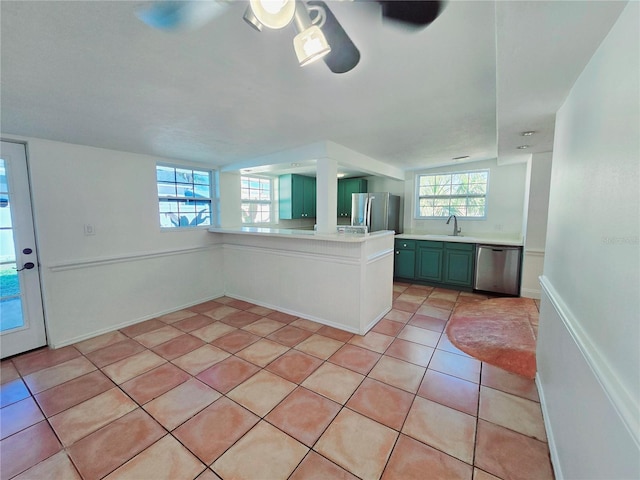 kitchen with plenty of natural light, appliances with stainless steel finishes, light countertops, a sink, and light tile patterned flooring