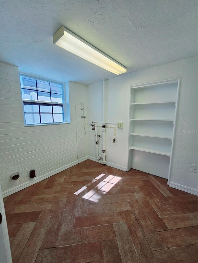 interior space with a textured ceiling, built in features, and baseboards