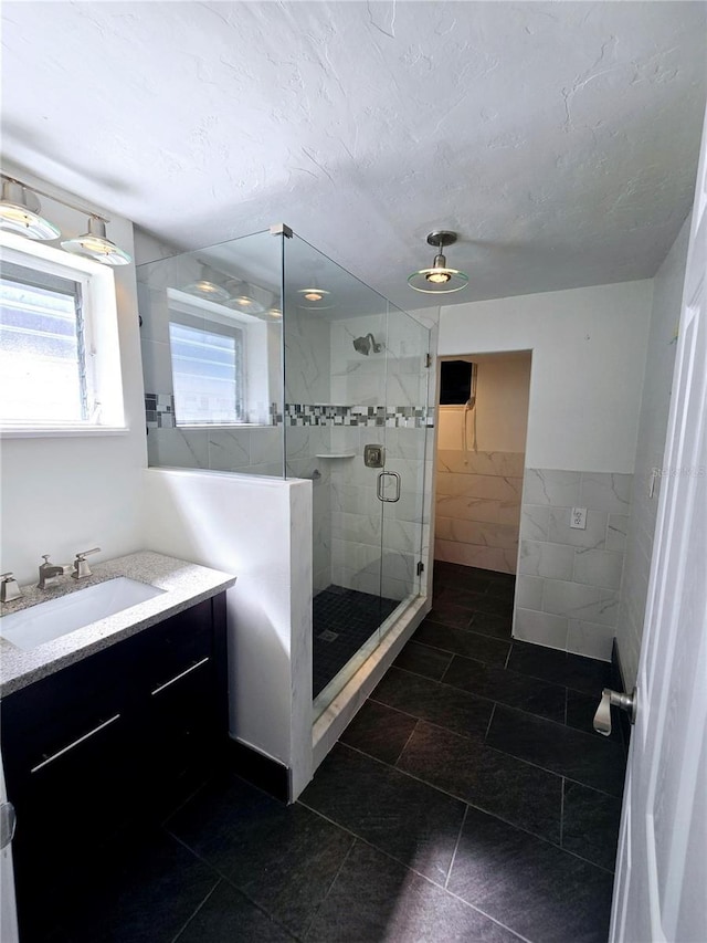 full bath with a textured ceiling, a stall shower, tile walls, and a healthy amount of sunlight