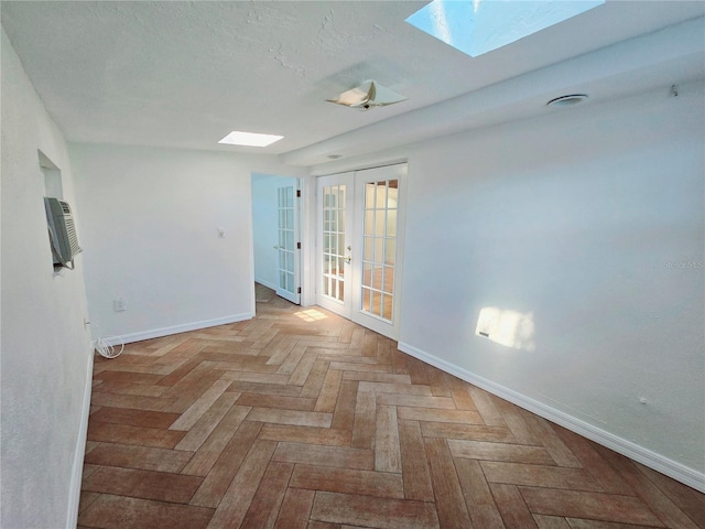 empty room featuring a textured ceiling, french doors, a skylight, and baseboards