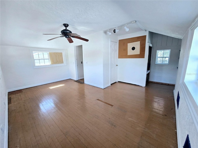 unfurnished room featuring ceiling fan, vaulted ceiling, a textured ceiling, baseboards, and hardwood / wood-style flooring