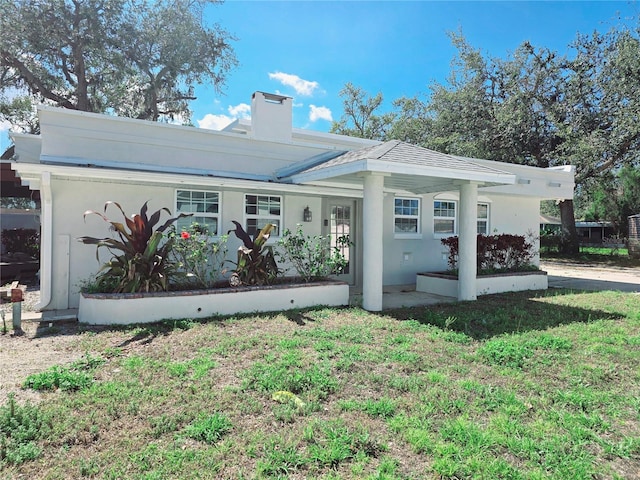 view of front of property with a front yard, a chimney, and stucco siding