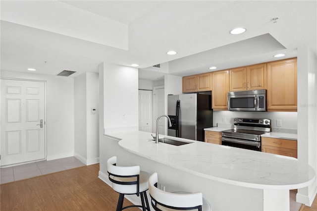 kitchen with a peninsula, a breakfast bar area, stainless steel appliances, and a sink