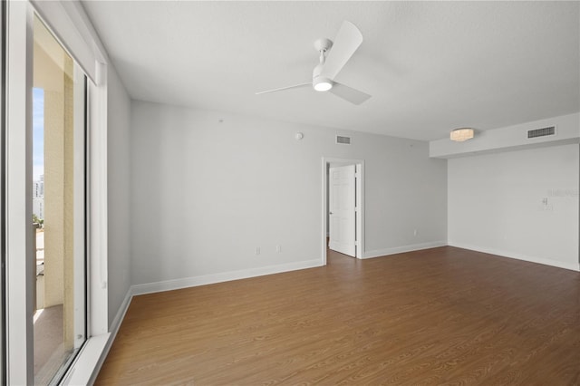 unfurnished room featuring a ceiling fan, visible vents, baseboards, and wood finished floors