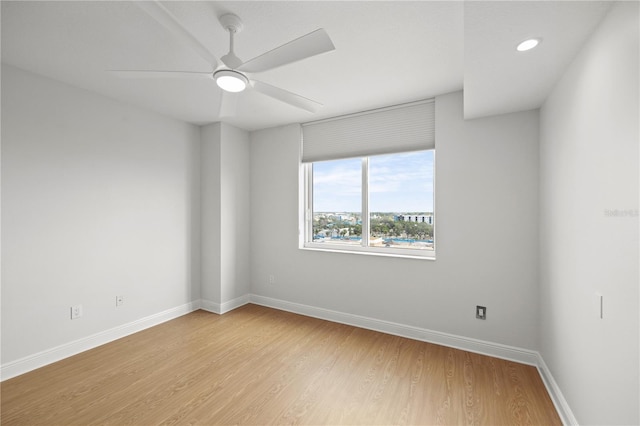 spare room with ceiling fan, light wood-style flooring, and baseboards