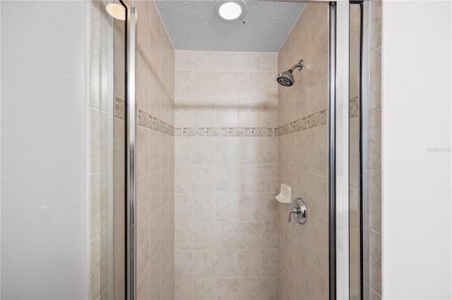 details featuring a shower stall and a textured ceiling