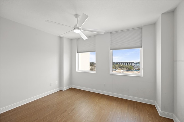 spare room with light wood-type flooring, ceiling fan, and baseboards