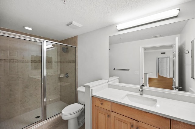 bathroom featuring toilet, vanity, a shower stall, and visible vents