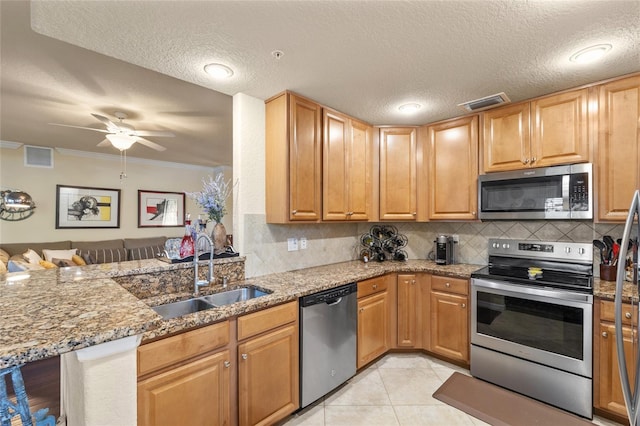 kitchen featuring stainless steel appliances, light stone counters, backsplash, and a sink