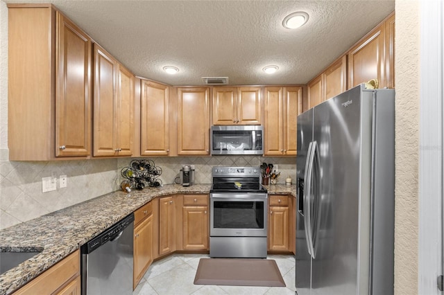 kitchen featuring stainless steel appliances, visible vents, light stone counters, and light tile patterned flooring