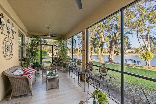 sunroom / solarium featuring a ceiling fan and a water view