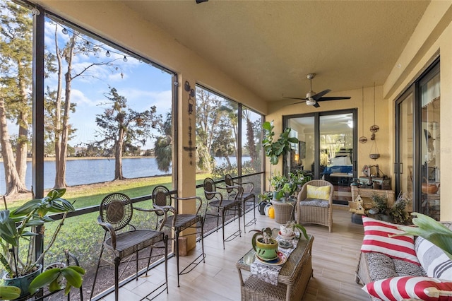 sunroom / solarium with a water view and a ceiling fan