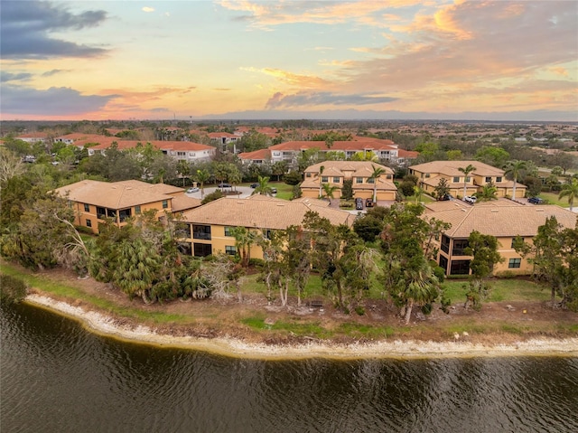 aerial view at dusk with a water view and a residential view