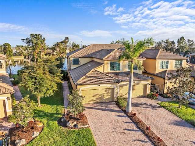 view of front of property featuring decorative driveway, an attached garage, a tile roof, and stucco siding