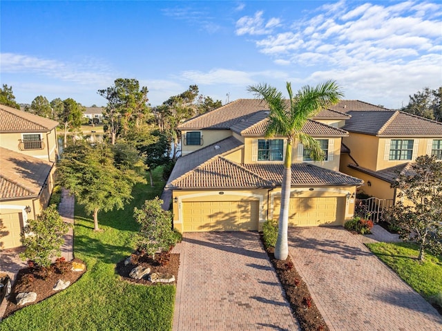 mediterranean / spanish home with a garage, decorative driveway, a tiled roof, and stucco siding