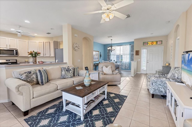 living room with baseboards, arched walkways, light tile patterned flooring, and ceiling fan with notable chandelier