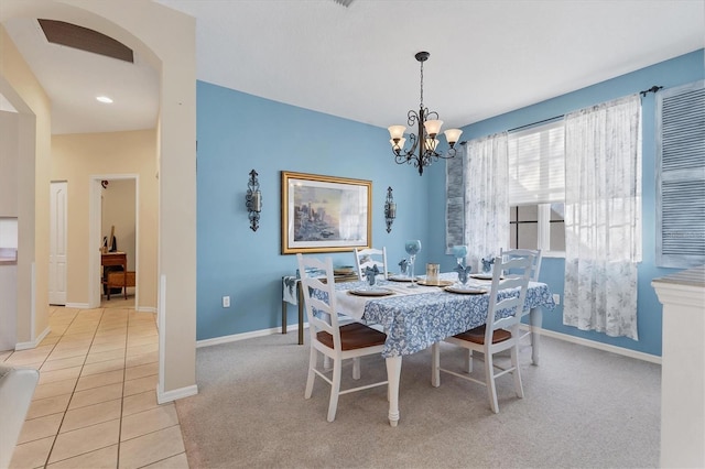 dining space with baseboards, a chandelier, light carpet, arched walkways, and light tile patterned flooring