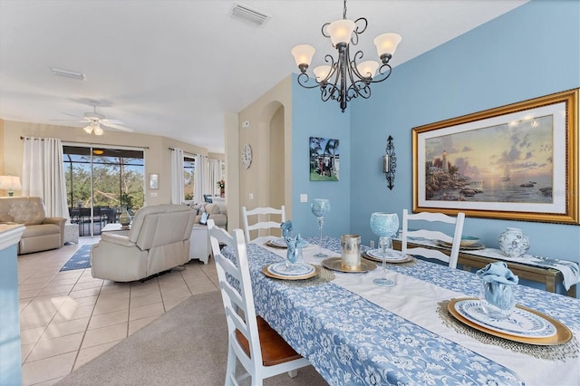 dining space with light tile patterned floors, visible vents, arched walkways, and ceiling fan with notable chandelier