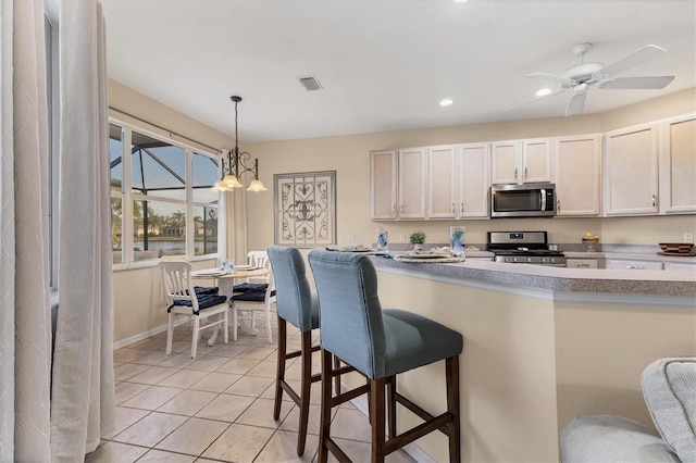 kitchen featuring light countertops, light tile patterned floors, a kitchen breakfast bar, hanging light fixtures, and stainless steel appliances