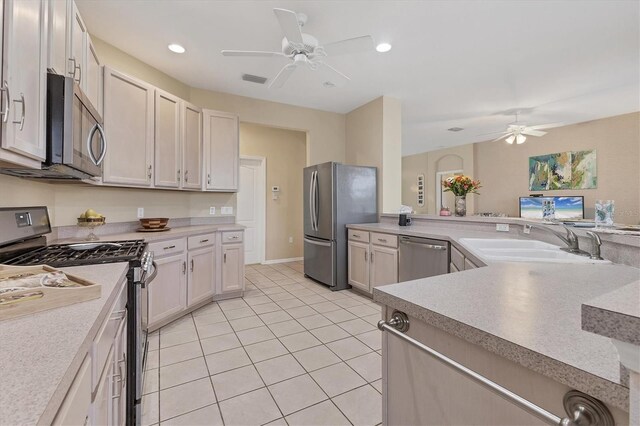 kitchen featuring light tile patterned floors, a ceiling fan, a sink, light countertops, and appliances with stainless steel finishes