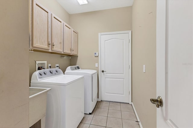 clothes washing area featuring light tile patterned floors, baseboards, cabinet space, a sink, and washer and clothes dryer