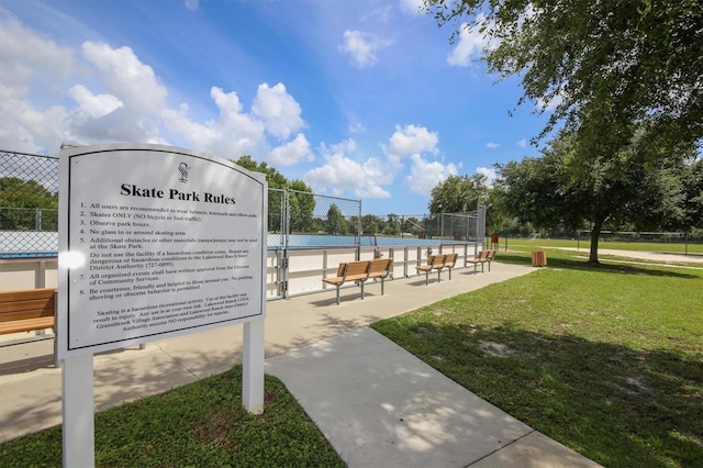 view of community featuring a tennis court, a lawn, and fence