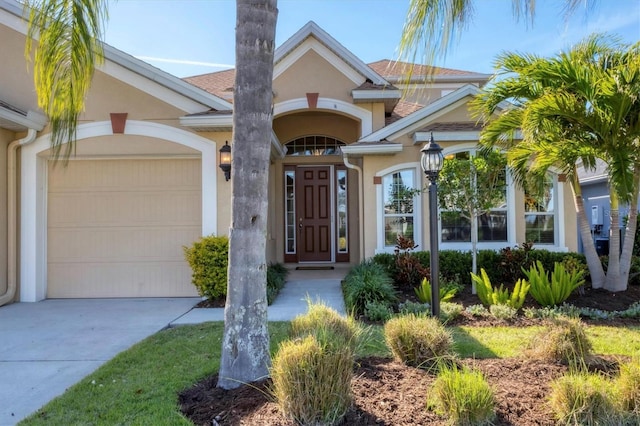 property entrance featuring driveway, an attached garage, and stucco siding