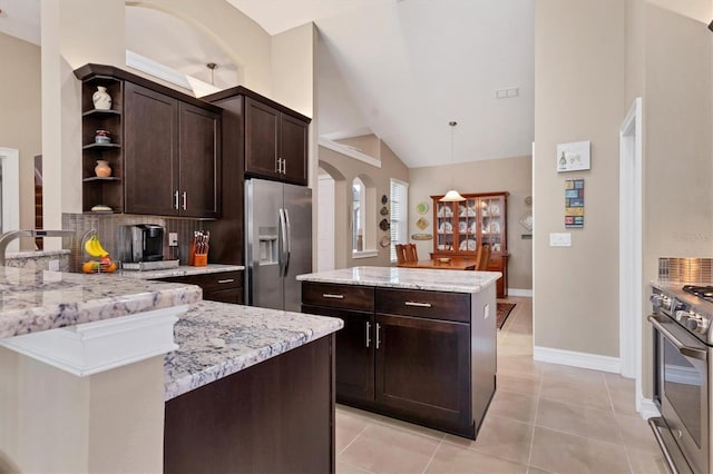 kitchen with arched walkways, stainless steel appliances, dark brown cabinets, hanging light fixtures, and open shelves