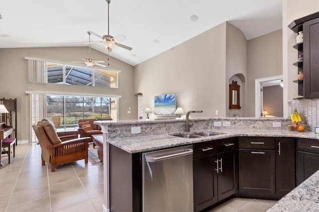 kitchen with light stone counters, a sink, stainless steel dishwasher, and light tile patterned floors