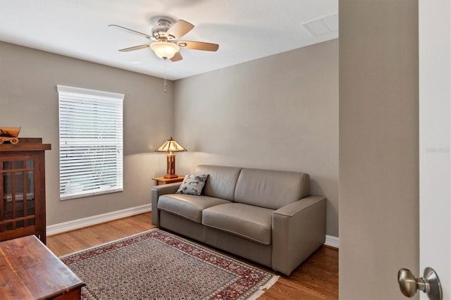 living area featuring light wood-style floors, baseboards, and a ceiling fan