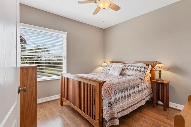 bedroom featuring a ceiling fan, baseboards, and wood finished floors