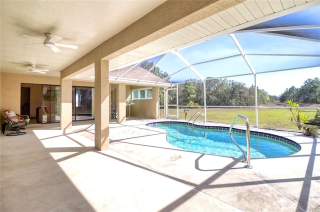 pool with ceiling fan, glass enclosure, a lawn, and a patio area