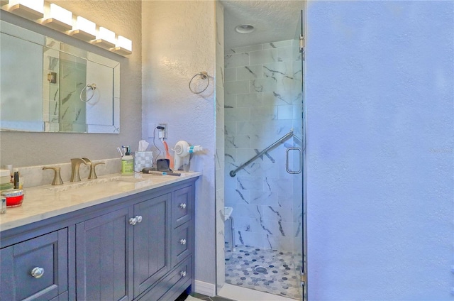 full bath featuring a textured wall, a stall shower, and vanity