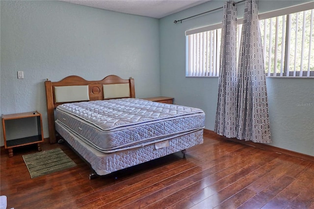 bedroom featuring multiple windows, hardwood / wood-style floors, and a textured wall