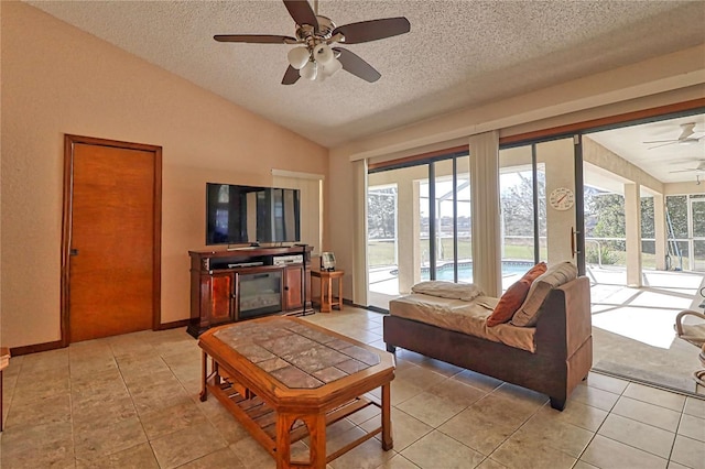 living room featuring lofted ceiling, light tile patterned flooring, ceiling fan, and a textured ceiling